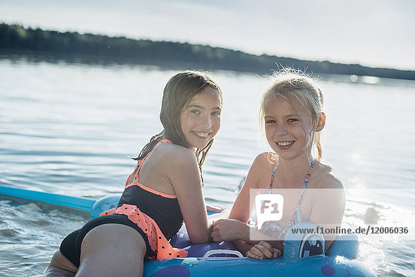 Portrait of two girls with swim toy at lake