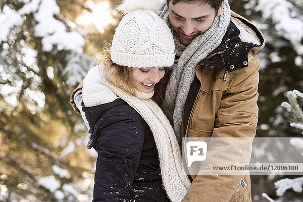 Happy young couple in snow-covered winter forest