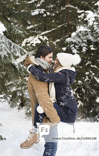 Happy young couple face to face in snow-covered winter forest