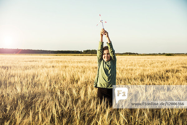 Mädchen im Getreidefeld stehend mit Miniatur-Windkraftanlage