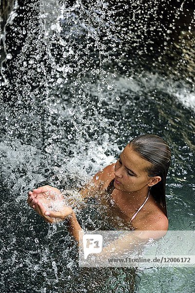 Junge Frau im Naturpool mit Wasserfall