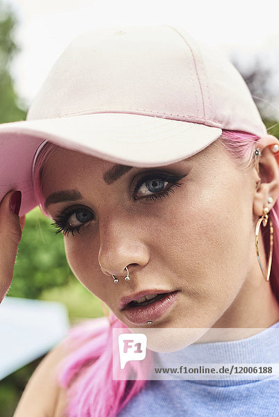 Porträt einer jungen Frau mit rosa Haaren und Piercings mit Mütze