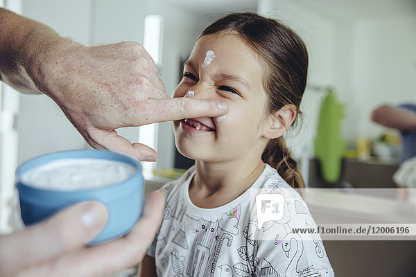 Father putting facial cream on daughter?s face
