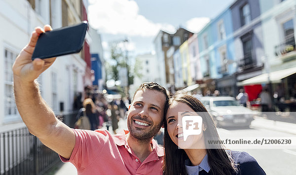 UK  London  Portobello Road  glückliches Paar nimmt Selfie mit Handy