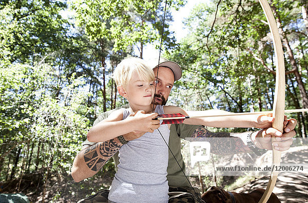 Vater und Sohn schießen mit Pfeil und Bogen im Wald