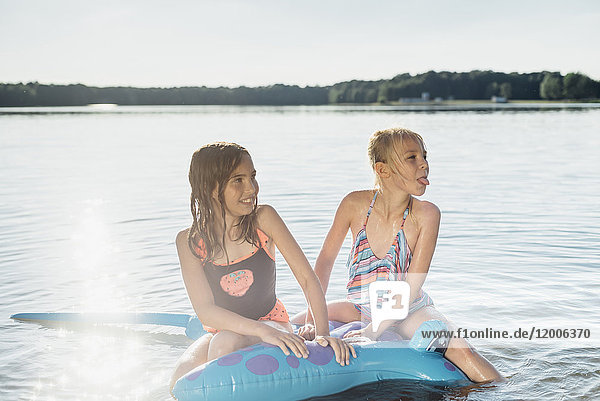 Two girls sitting on swim toy in the water
