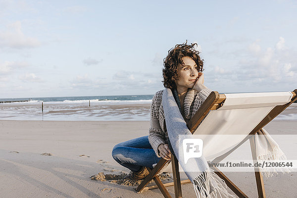 Frau auf Liegestuhl am Strand sitzend