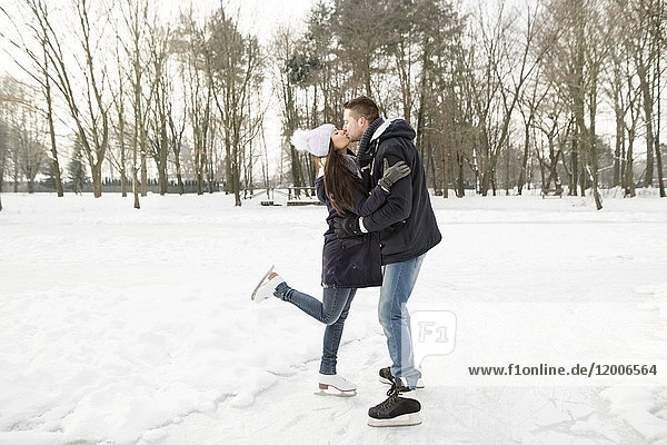 Couple ice skating on a frozen lake  kissing and embracing