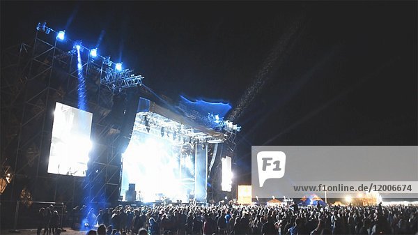 Menschenmenge bei Musikfestival in der Nacht  Blaulicht und Regen