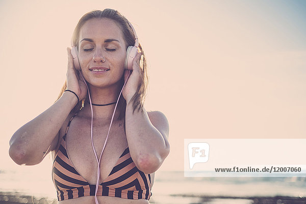 Caucasian woman listening to headphones on beach