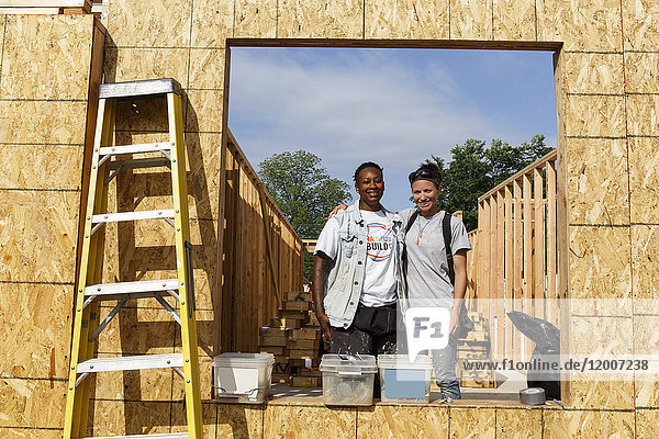 Porträt von Freiwilligen hinter einem Fensterrahmen auf einer Baustelle