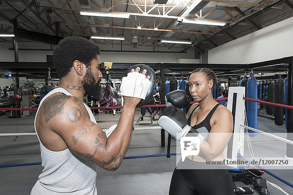 Black woman sparring with trainer in boxing ring