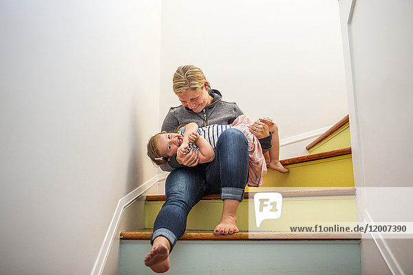 Kaukasische Mutter und Tochter spielen auf einer mehrfarbigen Treppe