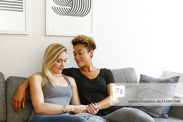 Women holding hands on sofa