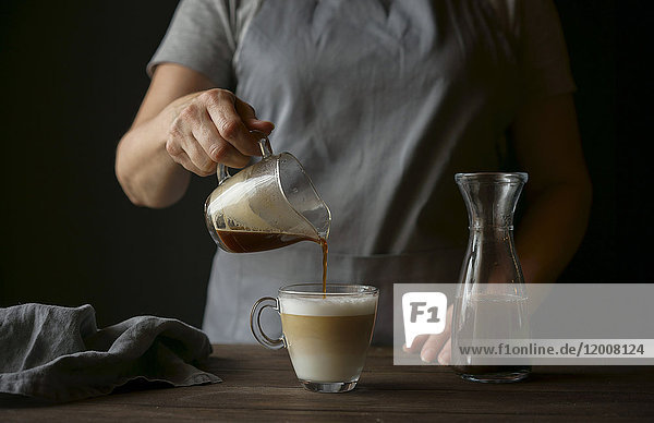 Kaukasische Frau gießt Kaffee in einen Milchkaffee