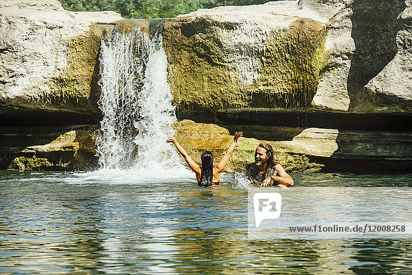 Kaukasisches Paar schwimmt in der Nähe eines Wasserfalls