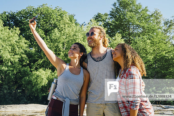 Friends posing for cell phone selfie outdoors