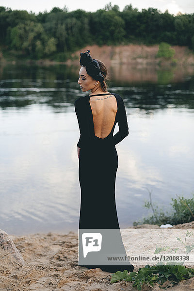 Middle Eastern woman wearing black dress near lake