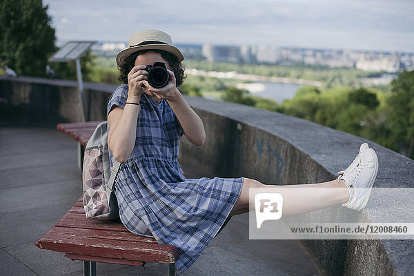 Caucasian woman sitting on bench photographing with camera
