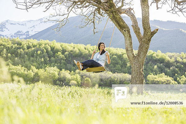Caucasian woman swinging on tree swing