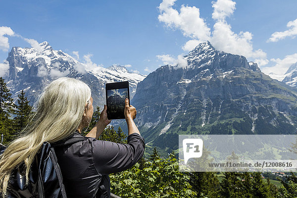Kaukasische Frau fotografiert Berg mit digitalem Tablet