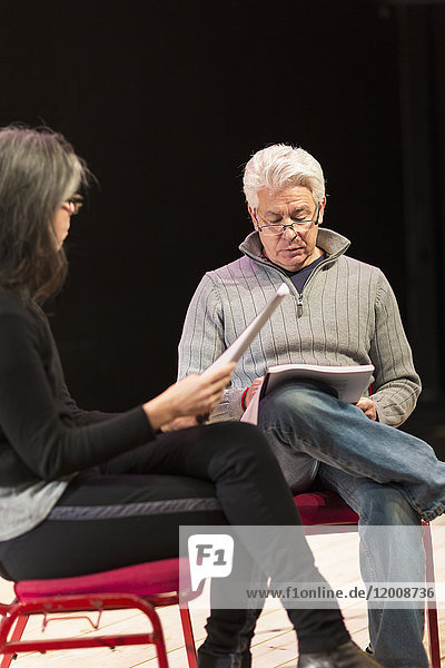 Hispanischer Mann und Frau lesen Drehbücher auf einer Theaterbühne