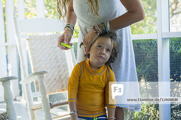 Kaukasische Mutter trägt Sonnenschutzmittel auf das Gesicht ihres Sohnes auf