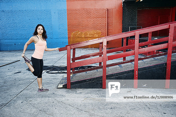 Mixed race woman stretching leg at loading dock