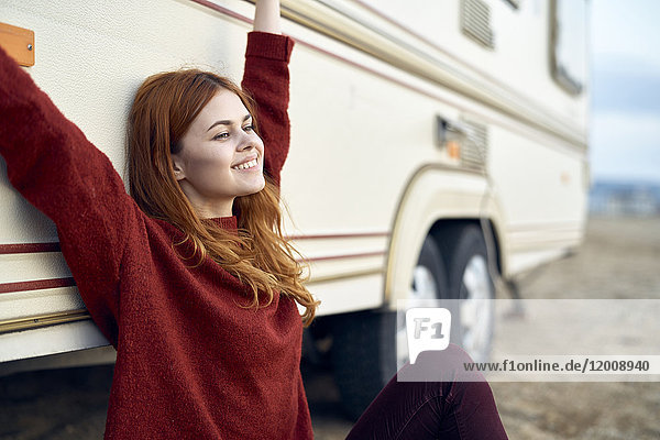 Caucasian woman stretching arms and leaning on motor home