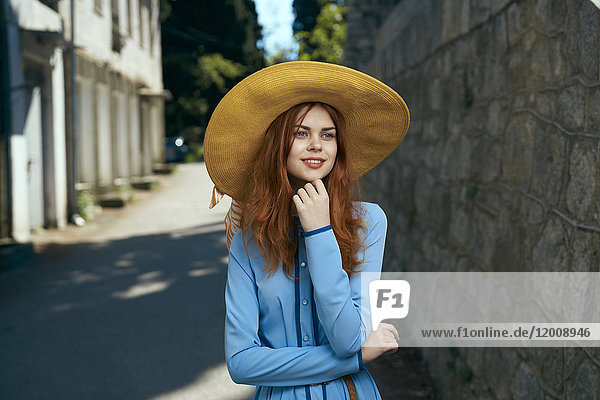 Nachdenkliche kaukasische Frau mit Hut in der Nähe einer Steinmauer