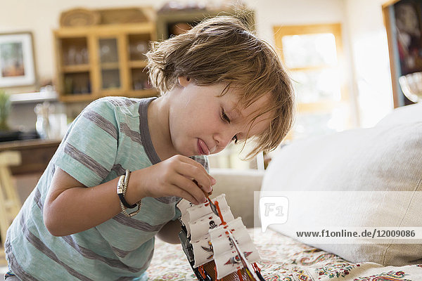 Caucasian boy playing with toy boat on sofa