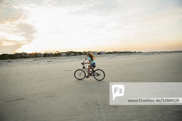 Kaukasisches Mädchen fährt Fahrrad am Strand