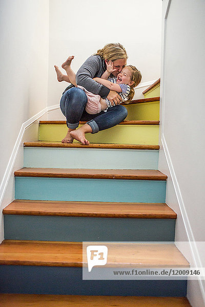 Kaukasische Mutter küsst Tochter auf der Treppe