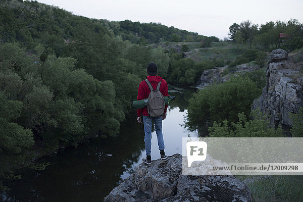 Kaukasischer Wanderer steht auf einem Felsen in der Nähe des Flusses