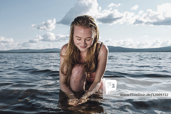 Kaukasisches Teenager-Mädchen kniend im Meer