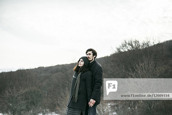 Kaukasisches Paar steht auf einem Hügel und entspannt sich