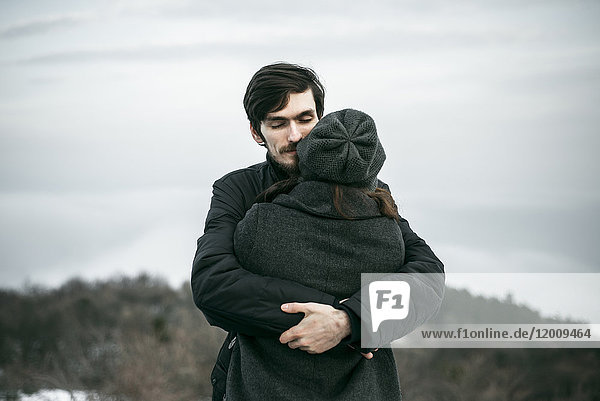 Kaukasisches Paar  das sich auf einem Hügel umarmt