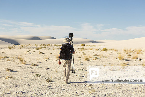Rückansicht eines kaukasischen Fotografen mit Stativ in der Wüste