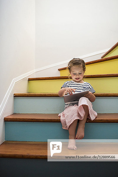 Kaukasisches Mädchen benutzt digitales Tablet auf einer Treppe