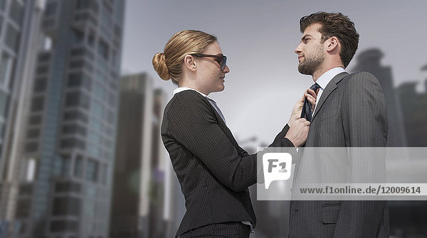 Kaukasische Geschäftsfrau passt Krawatte für Geschäftsmann an