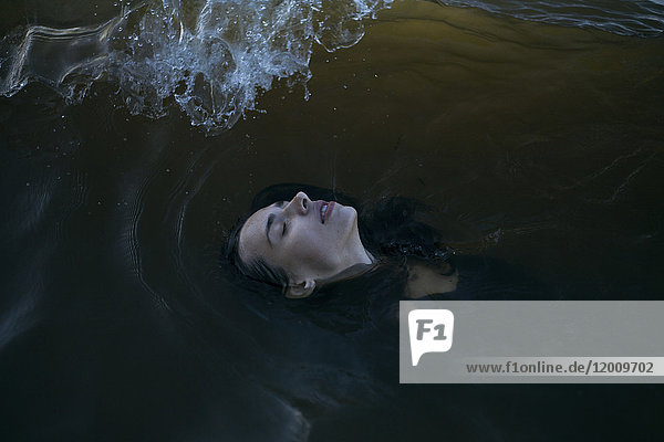 Kaukasische Frau schwimmt mit geschlossenen Augen im Meer
