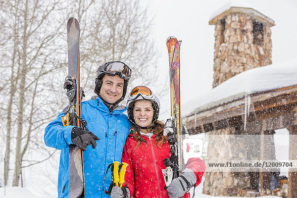 Porträt eines lächelnden kaukasischen Paares mit Skiern