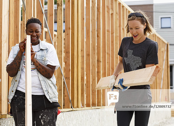 Volunteers carrying lumber at a construction site