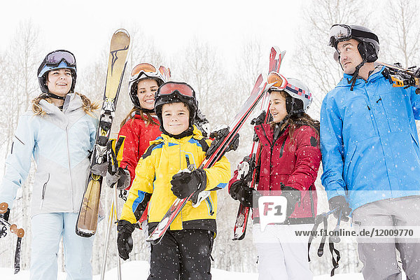 Smiling Caucasian family carrying skis in snow