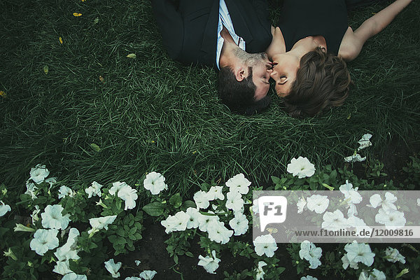 Kaukasisches Paar liegt im Gras und küsst sich
