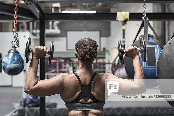 Black woman lifting dumbbells in gymnasium