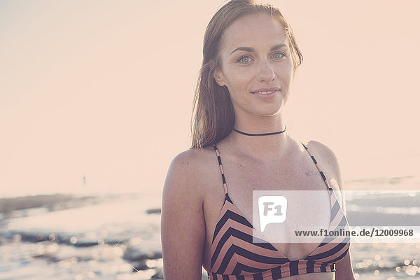 Lächelnde kaukasische Frau im Bikini am Strand