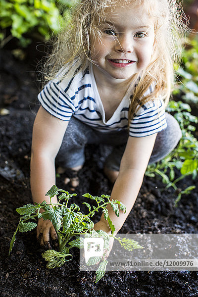 Kaukasisches Mädchen posiert mit Pflanze im Garten