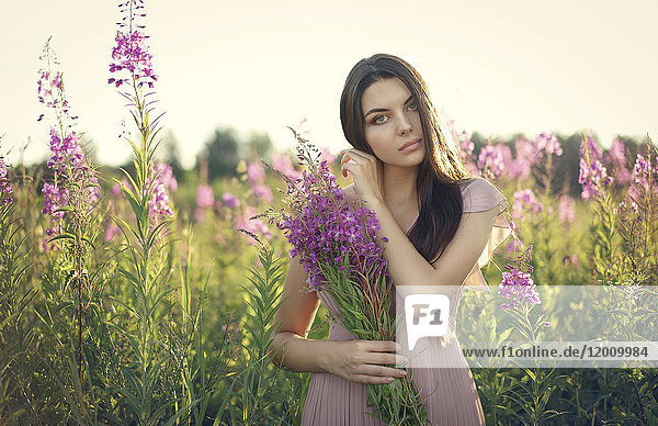 Porträt einer kaukasischen Frau  die Wildblumen auf einem Feld sammelt