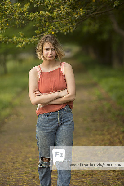 Caucasian teenage girl with arms crossed in park